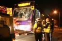 Police wait while the bus involved in an accident with a cyclist is towed away