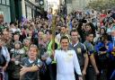 Luke Young carries the Olympic torch along Shamble