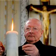 Father Pat Smith lights a  candle for Sean Hamilton at The Church of Our Lady, in Gale Lane, Acomb