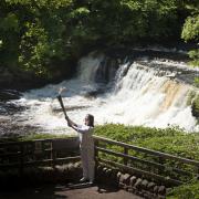 Torchbearer Lucy Gale poses with the Olympic Flame in front of Aysgarth Falls earlier today