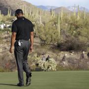 A disconsolate Tiger Woods walks off a course into the sunset