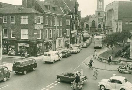 It's 1967 and the man on his scooter at the bottom of the picture has no crash helmet, traffic's jammed back from Coppergate, but the Army and Navy Stores are open for business.