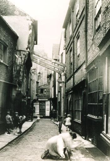 The sign at the end of this street reads Little Shambles.  Note the three pieces of timber precariously supporting the building on the left. 