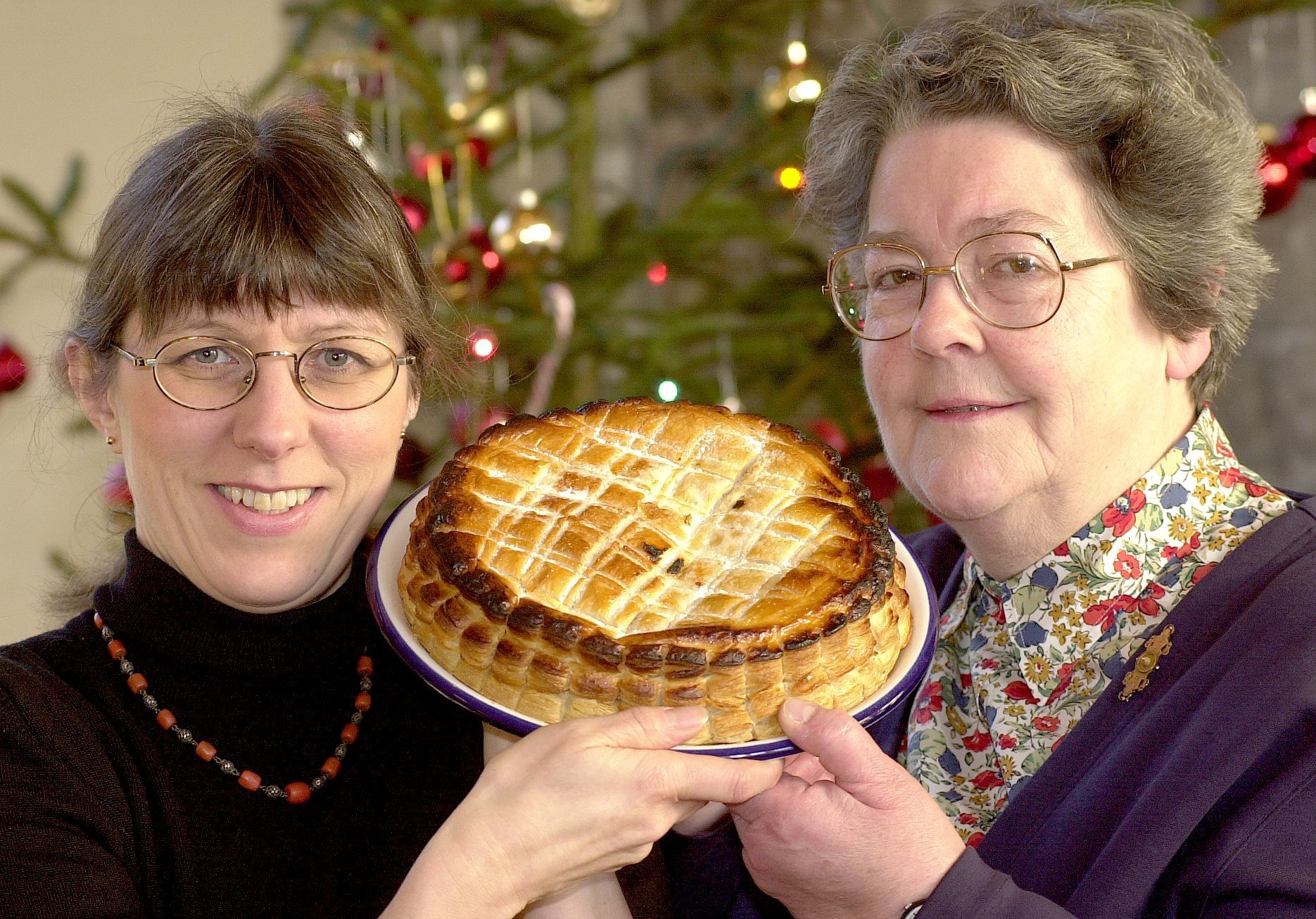 Laura Mason, left, and Ann Rycraft holding the Twelfth Night Cake for the Twelfth Night party at Jacobs Well where they will present a cheque for £400 to St Leonards Hospice - from The Press, January 2001
