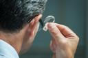 Man inserts hearing aid in his ear.