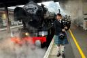 A tartan-clad piper serenades Flying Scotsman as it leaves York Station this morning
