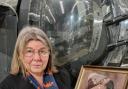 Celia standing by the rear gun turret of the Halifax Mk III bomber at the Yorkshire Air Museum, holding a photo of her uncle Edwin Bowen