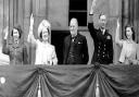 Prime Minister Winston Churchill looks on, centre, as King George VI, Queen Elizabeth,  then-Princess Elizabeth (left) and Princess Margaret, wave to crowds gathered below, from the balcony of Buckingham Palace on VE Day, May 8, 1945