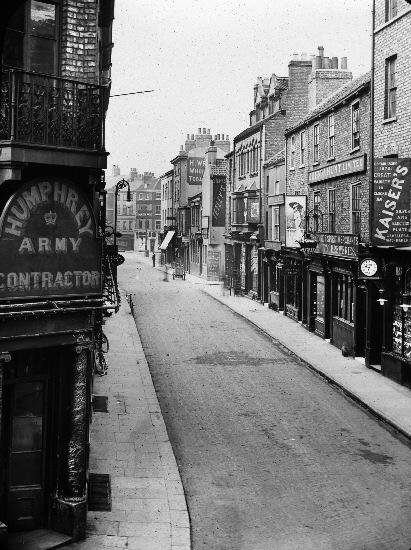This is York, in 1890. Well done to anyone who correctly identified it as Church Street. The building in the front-left corner is now Thomas The Baker, and the building to the left of the Kaiser's sign is the Golden Lion pub. 