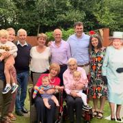 Alf Patrick celebrates his 100th birthday with his family, with a cardboard cut-out of the Queen on the right