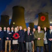 The illuminated poppy at Drax Power Station with veterans  from the station who organised its Poppy Appeal