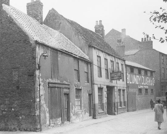 This image shows a woman walking down North Street in the 1940s. The premises shown were demolished in the 1960s to make way for the Viking Hotel, now the Park Inn Hotel. Blundy Clark and Co. were coal, gravel and cement merchants.