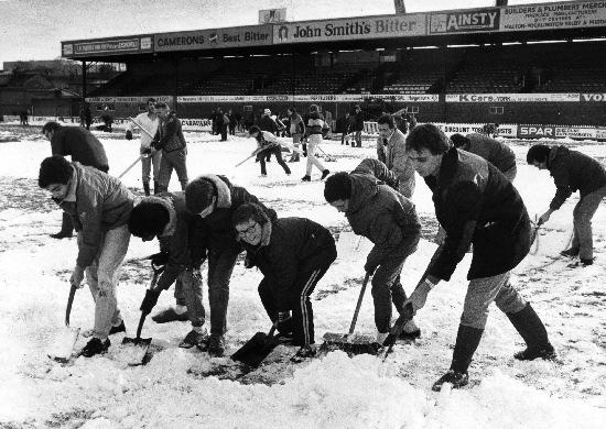 York City fans clear snow from the Bootham Crescent pitch, before the famous FA Cup victory over Arsenal in 1985.