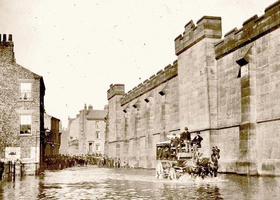 Tower Street, pictured during the flood of 1892. The Prison Wall on the rightm, which hides Clifford's Tower, was demolished in the early 1930s.