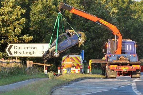 The blue Renault Clio is hoisted away by a crane after the crash on the A64 in which one man died